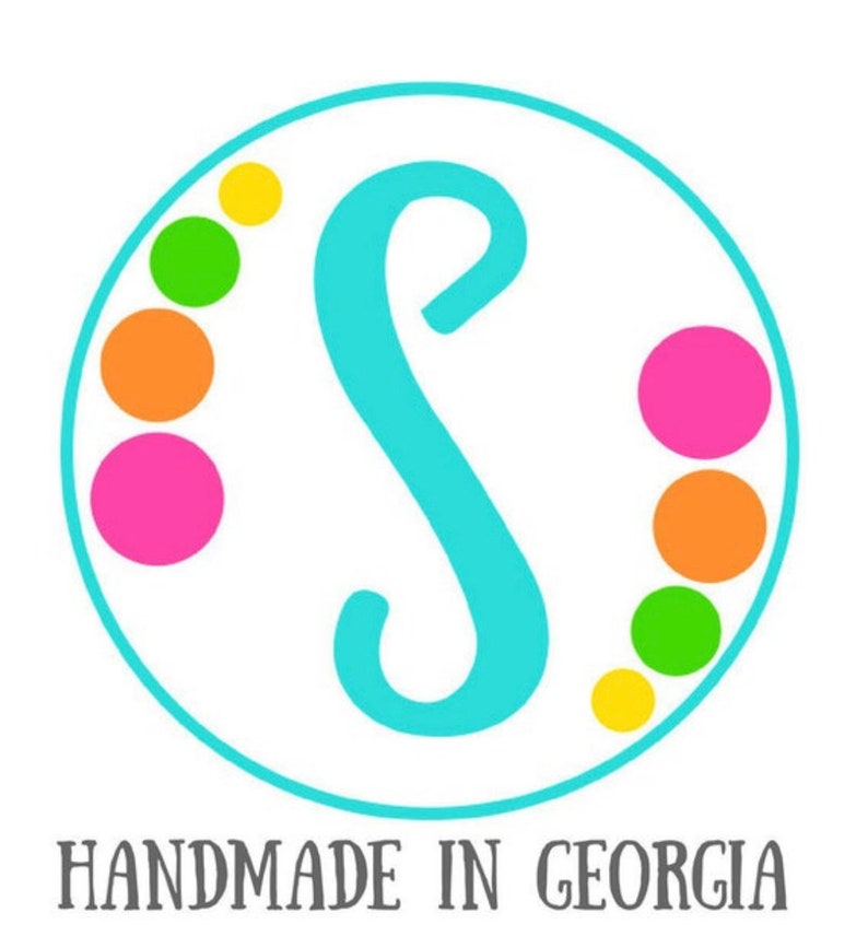 May include: A turquoise letter S in a white circle with a border of yellow, green, orange, and pink dots. The text "HANDMADE IN GEORGIA" is below the circle.