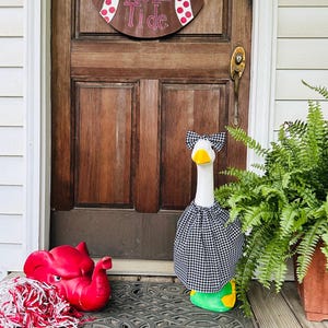 May include: A decorative goose wearing a black and white checkered dress and bow tie, with a yellow beak and green base. A red elephant statue with a pom-pom and a wooden sign that says "Roll Tide" are also visible.