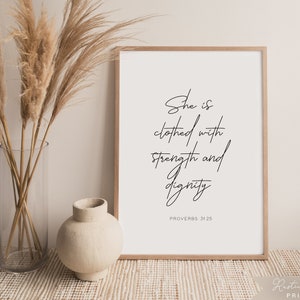 May include: A framed print with a white background and black text that reads "She is clothed with strength and dignity" and "Proverbs 31:25".