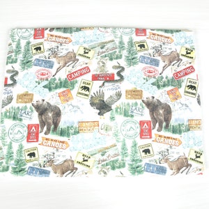 May include: White fabric with a repeating pattern of camping and nature-themed illustrations. The pattern includes bears, deer, eagles, trees, and signs with text like "Big Bear Lake Canoes", "Camping", "Bear Crossing", and "Colorado Trail".