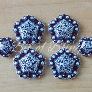 May include: Set of five silver-toned conchos with a floral design and red rhinestone accents.