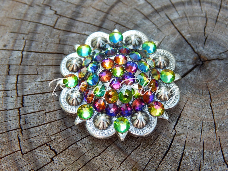 Pode incluir: Uma fivela redonda decorativa de cor prateada com um design floral. A fivela &eacute; adornada com uma variedade de pedras de imita&ccedil;&atilde;o iridiscentes em tons de verde, azul, roxo, laranja e vermelho.