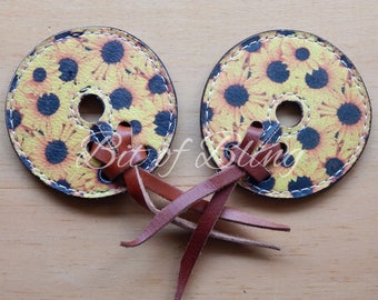 May include: Two brown leather sunflower-patterned bit straps with brown leather laces. The straps are tied together in a knot.