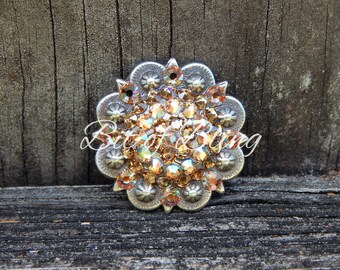 May include: A silver and gold-toned metal concho with a floral design and a center filled with sparkling amber-colored rhinestones.
