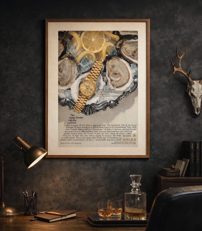 May include: A framed vintage advertisement poster featuring a gold Rolex Oyster watch resting on a silver platter of oysters and lemon slices. The text includes The Rolex Oyster falls the taste test and details about the watch movement.