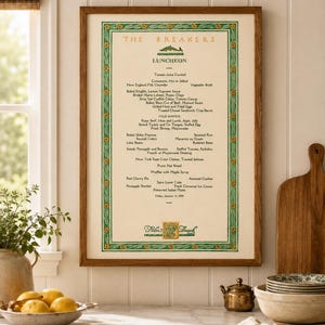 May include: A framed vintage menu titled The Breakers Luncheon, dated Friday, January 13, 1939, Palm Beach. The menu features a green floral border, a fish illustration, and a list of food items printed in black text on a cream-colored background.