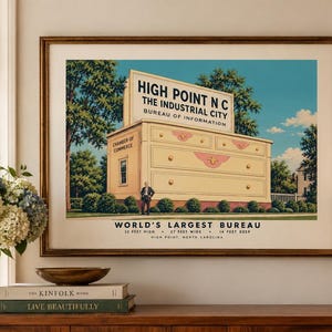 Puede incluir: Una impresión enmarcada de estilo vintage que representa el buró más grande del mundo en High Point, Carolina del Norte. La ilustración muestra un edificio masivo con forma de cómoda con el texto High Point NC The Industrial City.