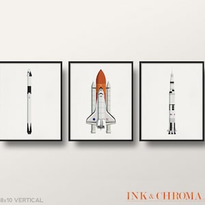 May include: Set of three 8x10 inch vertical prints featuring illustrations of a space shuttle, a rocket, and a satellite. The prints are in black frames and are displayed on a white wall.