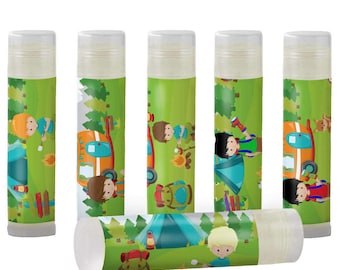 May include: Six green and white lip balm tubes with a camping theme. Each tube features a cartoon illustration of children camping, a camper van, and a campfire.
