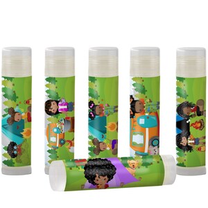 May include: Six green and white lip balm tubes with colorful illustrations of girls camping. The illustrations include a tent, a campfire, a camper van, and trees.