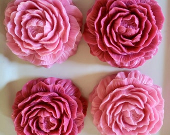 May include: Four pink and red rose-shaped soaps on a white background. The soaps are arranged in a square pattern.