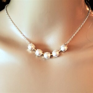 May include: A silver chain necklace with five white pearl beads.