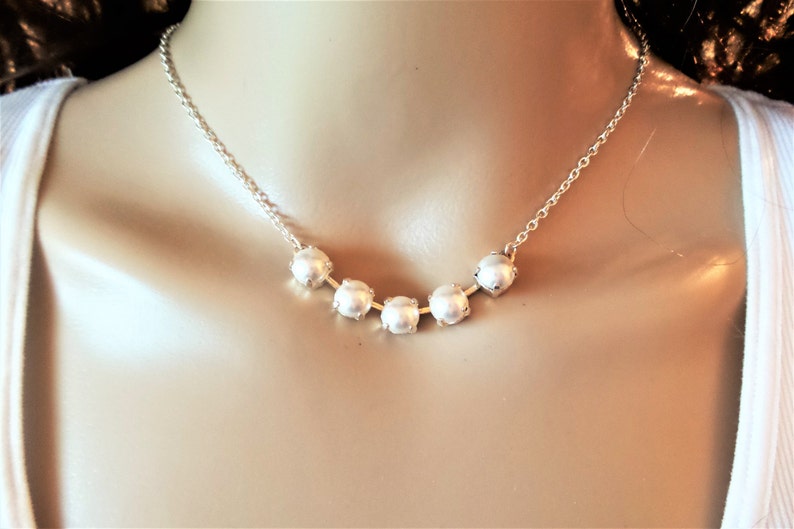 May include: A silver chain necklace with five white pearl beads.