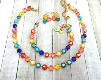 May include: A rainbow-coloured crystal necklace, bracelet and earrings set. The jewellery is made with gold-toned metal and features round, faceted crystals in shades of red, orange, yellow, green, blue and purple.