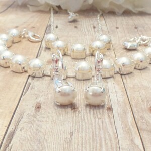 May include: A set of pearl jewelry including a necklace, bracelet, and earrings. The jewelry is made of silver and features large, white pearls.