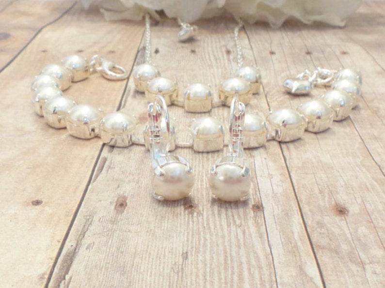 May include: A set of pearl jewelry including a necklace, bracelet, and earrings. The jewelry is made of silver and features large, white pearls.