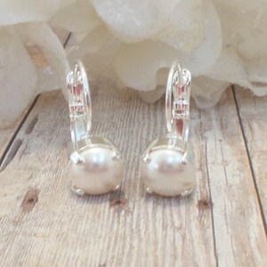 May include: A pair of silver earrings with a white pearl in the center of each earring.
