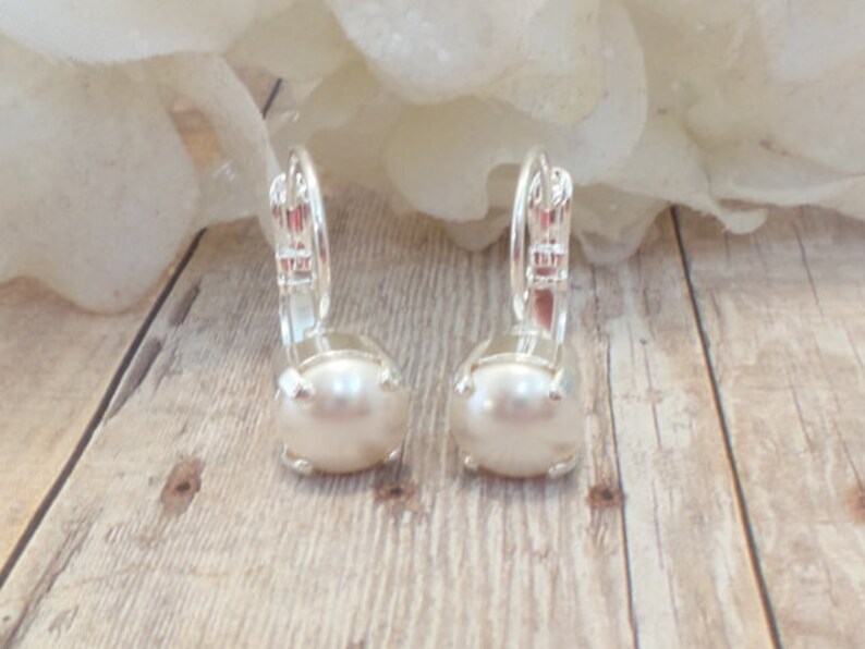 May include: A pair of silver earrings with a white pearl in the center of each earring.