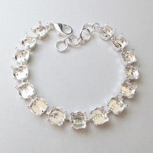 May include: Silver bracelet with multiple settings for rhinestones or other embellishments. The bracelet has a lobster clasp closure.