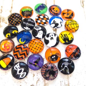 May include: A collection of 20 Halloween themed glass cabochons. The cabochons feature various Halloween designs, including ghosts, pumpkins, bats, spiders, and candy corn. The cabochons are perfect for crafting projects, such as jewelry making, scrapbooking, and card making.