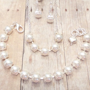 May include: A set of pearl jewelry featuring a necklace, bracelet, and earrings. The jewelry is made with white pearls and silver accents.