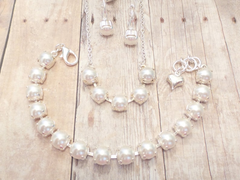 May include: A set of pearl jewelry featuring a necklace, bracelet, and earrings. The jewelry is made with white pearls and silver accents.