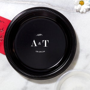 May include: Black plastic disposable plate with white text that reads "A & T" and "09.26.24".
