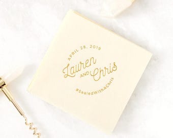 Könnte beinhalten: Eine quadratische, cremefarbene Papierserviette mit goldfarbenem Folienaufdruck, der "APRIL 28, 2019", "Lauren AND Chris" und den Hashtag "#SealedWithAChris" zeigt. Die Serviette liegt zwischen einem goldfarbenen Korkenzieher und einem Flaschenverschluss.