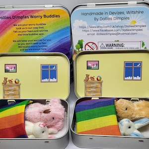 May include: Two small tin boxes with rainbow lids. Each box contains a stuffed animal and a rainbow blanket. The boxes are labelled "Dollies Dimples Worry Buddies" and "Handmade in Devizes, Wiltshire by Dollies Dimples".