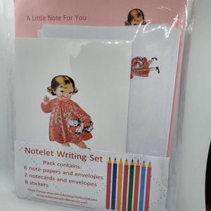 May include: A pink and white notelet writing set featuring a girl illustration on the front. The set includes 6 note papers, 2 note cards, 8 stickers, and envelopes. The text on the front reads "A Little Note For You" and "Notelet Writing Set".