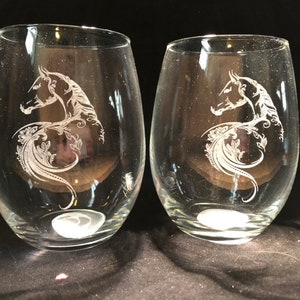 May include: Two clear glass wine glasses with an etched design of a horse's head and floral patterns.