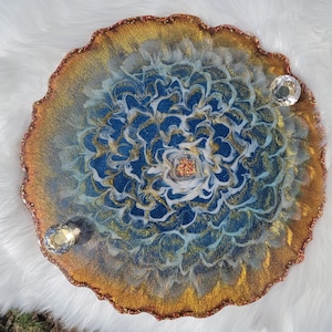 May include: A round resin tray with a blue, white, and gold swirl design. The tray has a gold glitter rim and is decorated with clear crystal embellishments.
