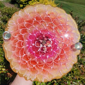 May include: A resin tray with a pink and orange flower design. The tray has a gold glitter finish and is decorated with two clear crystal embellishments.