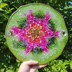 May include: A green resin tray with a pink and white floral design and gold glitter accents. The tray has two clear crystal knobs on the sides.
