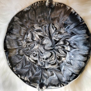 May include: A black and silver resin tray with a swirling, marbled design. The tray has a raised edge and two crystal-like knobs.