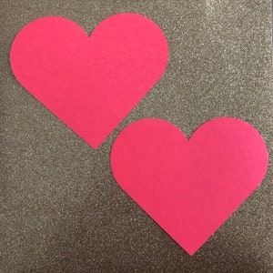 May include: Two red paper hearts on a sparkly silver background.