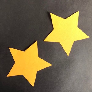 May include: Two yellow paper stars on a black background.