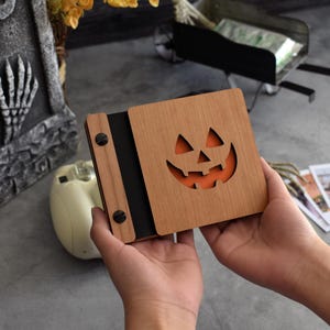A wooden Halloween scrapbook with a Jack-O&#39;-Lantern cover, perfect for preserving kids&#39; or couples&#39; Halloween memories through the years.