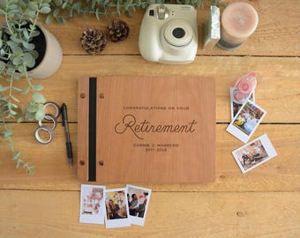 May include: A rectangular wooden photo album with a black spine and metal binding screws. The cover is engraved with the text: CONGRATULATIONS ON YOUR RETIREMENT, CONNIE C MARRERO, 2017-2024. The album is surrounded by small instant photos.