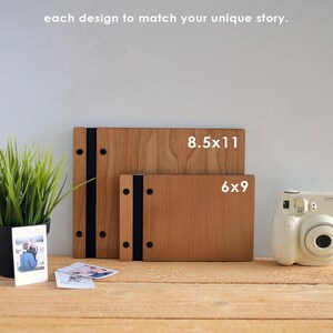 May include: Two wooden photo albums, one 8.5x11 inches and one 6x9 inches, with black ribbon closures and metal accents. The albums are on a wooden surface with a vintage camera and photos.
