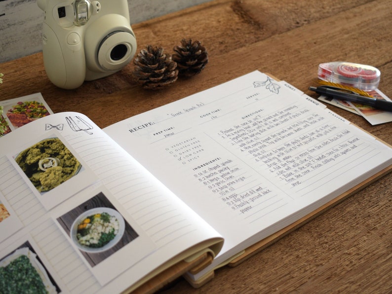 May include: Open recipe book with a white cover and lined pages. The book is open to a recipe for "Sweet Bread Roll". The recipe includes a list of ingredients, prep time, cook time, and directions. There are also several Polaroid photos of food in the book.