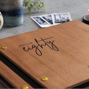 Engraved wooden birthday guest book in cherry finish with customized cover and minimalist design engraving.