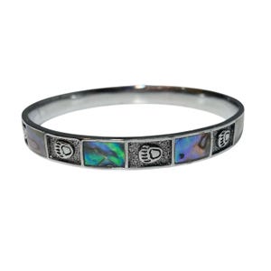 May include: A silver-coloured bangle bracelet with alternating rectangular inlays of iridescent abalone shell and bear paw prints. The bracelet has a smooth finish and a circular design.