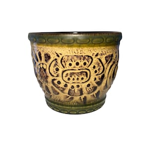 May include: A ceramic plant pot with a cream-coloured base and dark brown embossed floral design. The rim and base feature a green trim. The interior is dark brown. Suitable for indoor or outdoor use.