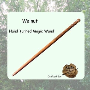 Puede incluir: Una varita mágica larga y delgada, torneada a mano en madera de nogal marrón, con un eje liso y cónico y un mango texturizado. El texto en la imagen dice: Walnut, Hand Turned Magic Wand, Crafted By: The Lathe JUNKIE, Helping Trees Live On Through Art.
