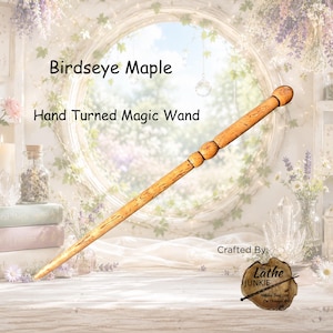 Puede incluir: Una varita mágica de arce ojo de perdiz torneada a mano en color marrón claro, con un eje cónico suave y un mango redondeado. La madera presenta un patrón de grano natural moteado. El texto dice: Birdseye Maple, Hand Turned Magic Wand, Crafted By: The Lathe Junkie.