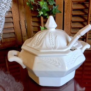 May include: White ceramic soup tureen with a lid and a ladle. The tureen has a wheat design and is decorated with a raised wheat pattern.