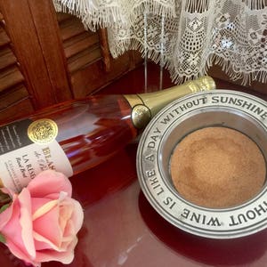 May include: A silver wine coaster with the inscription "A day without sunshine, a dinner without wine is like..."  A bottle of Blas de Bo La Reserve Rose Brut sparkling wine is in the background.