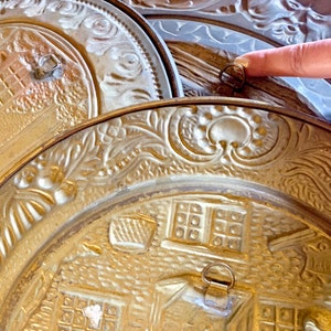 K&ouml;nnte beinhalten: Drei goldfarbene Metallplatten mit aufwendigen Pr&auml;gemustern. Die Platten sind &uuml;bereinander gestapelt, und die oberste Platte hat einen daran befestigten Ring.