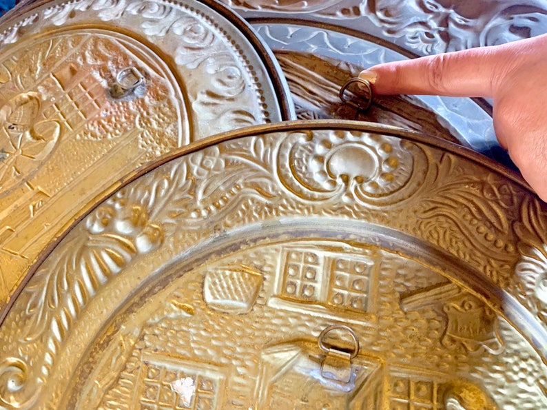 K&ouml;nnte beinhalten: Drei goldfarbene Metallplatten mit aufwendigen Pr&auml;gemustern. Die Platten sind &uuml;bereinander gestapelt, und die oberste Platte hat einen daran befestigten Ring.